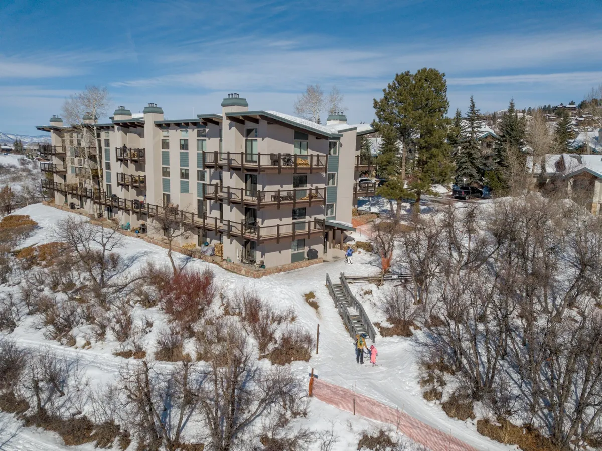 The multi-story building stands amidst a snow-covered landscape, with a walking path leading up to the entrance. The area is immaculate, with no indication of pets or animals, suggesting strict adherence to the pet-free policy. The setting is peaceful and inviting, ideal for those prioritizing health and cleanliness.