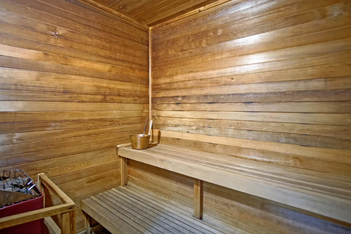 A cozy sauna with wooden benches and walls, paired with a traditional bucket and ladle, creates a calming environment ideal for unwinding and self-care rituals after outdoor activities.