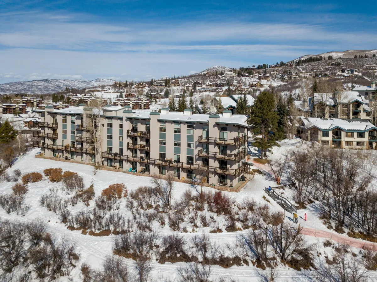 This image captures the four-story property building nestled in a serene, snow-covered landscape. The building is surrounded by pristine white snow, with nearby trees and shrubs enhancing the sense of natural tranquility. The exterior appears well-maintained, with no visible pet or animal presence, reinforcing a sense of cleanliness and order.